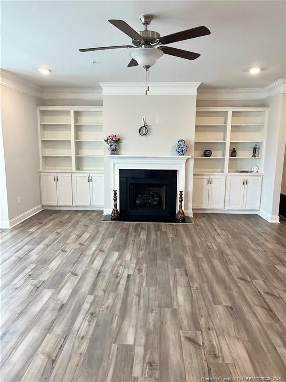 unfurnished living room with a ceiling fan, wood finished floors, and ornamental molding