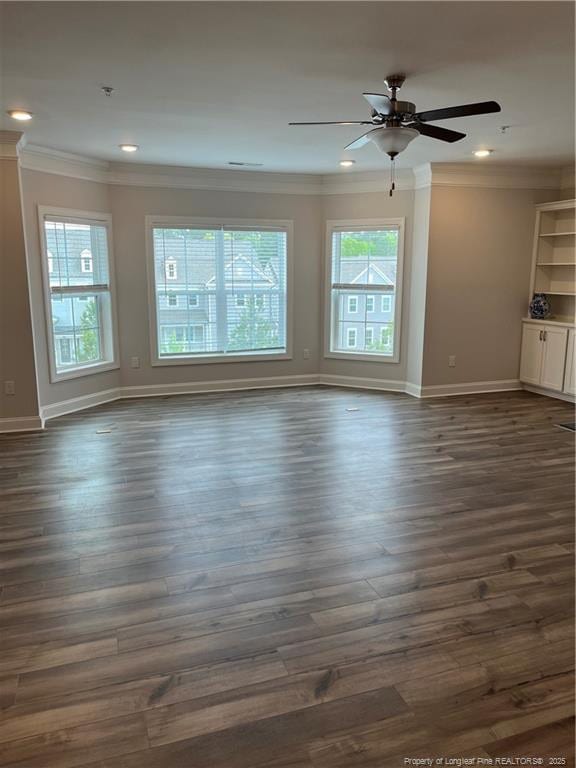 unfurnished living room featuring dark wood-type flooring, ornamental molding, and baseboards