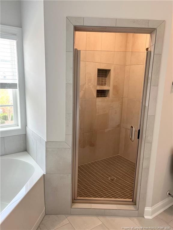 full bath featuring a stall shower, a garden tub, and tile patterned flooring