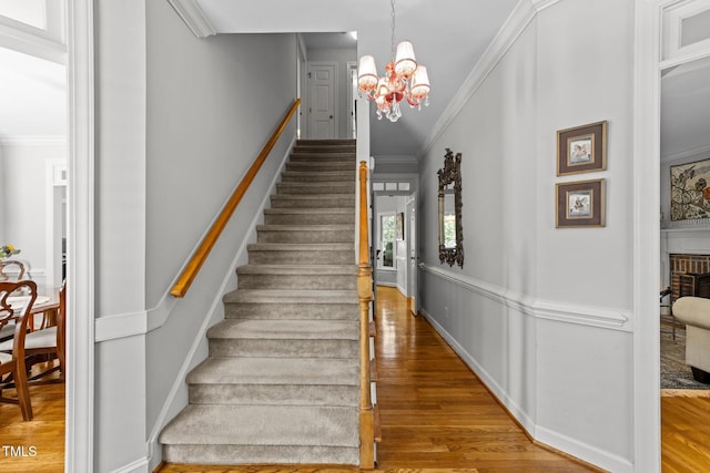2520 Ashley Ct, Raleigh, NC 27607 - stairway featuring ornamental molding, an inviting chandelier, wood finished floors, and a fireplace
