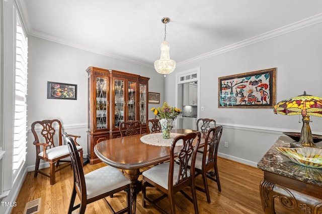 2520 Ashley Ct, Raleigh, NC 27607 - dining room featuring light wood-style flooring, crown molding, a chandelier, and visible vents