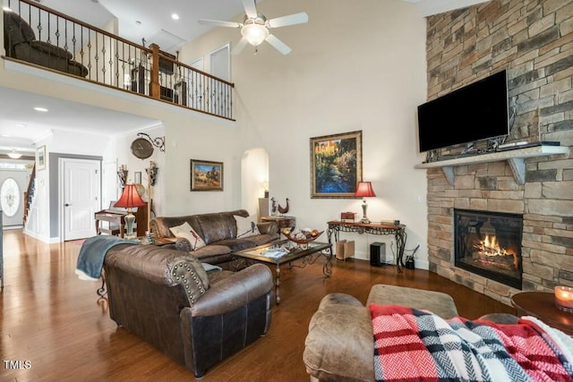 12808 Edsel Dr, Raleigh, NC 27613 - living room with arched walkways, a high ceiling, a stone fireplace, a ceiling fan, and wood finished floors
