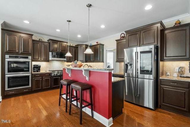 12808 Edsel Dr, Raleigh, NC 27613 - kitchen featuring stainless steel appliances, dark brown cabinetry, a breakfast bar, and crown molding