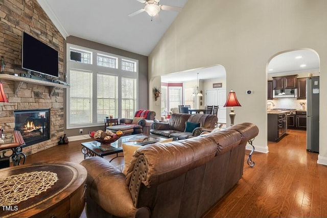 12808 Edsel Dr, Raleigh, NC 27613 - living room featuring a stone fireplace, ceiling fan, high vaulted ceiling, arched walkways, and wood finished floors