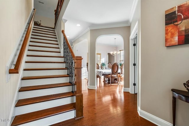 12808 Edsel Dr, Raleigh, NC 27613 - stairs with baseboards, an inviting chandelier, crown molding, arched walkways, and wood finished floors
