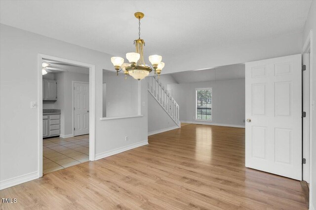 1517 Laughridge Dr, Cary, NC 27511 - unfurnished dining area with light wood-type flooring, a chandelier, stairs, and baseboards