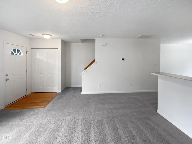 interior space with carpet, a textured ceiling, and baseboards
