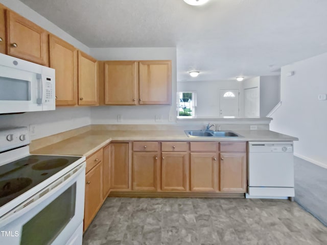 kitchen with light countertops, a peninsula, a sink, and white appliances