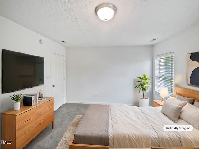 carpeted bedroom featuring visible vents, baseboards, and a textured ceiling