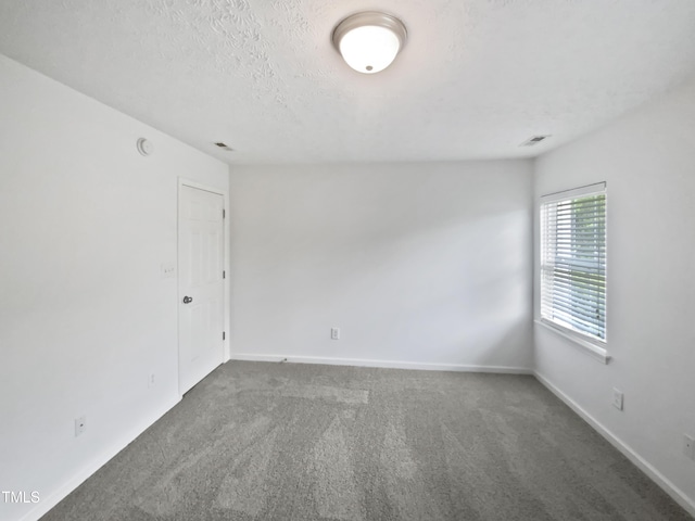 spare room featuring visible vents, baseboards, carpet flooring, and a textured ceiling