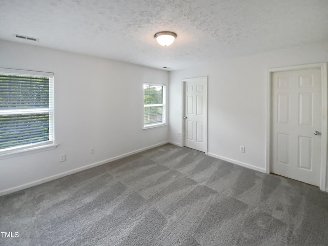 unfurnished bedroom featuring carpet, visible vents, baseboards, and a textured ceiling