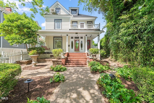 view of front of property featuring covered porch, fence, and a balcony