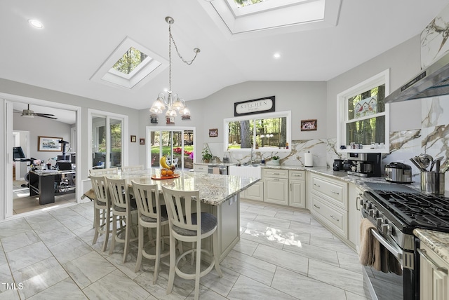 kitchen with stainless steel gas range oven, a kitchen breakfast bar, marble finish floor, and light stone counters