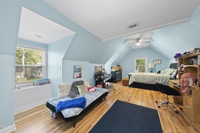 bedroom with visible vents, wood finished floors, vaulted ceiling, and multiple windows