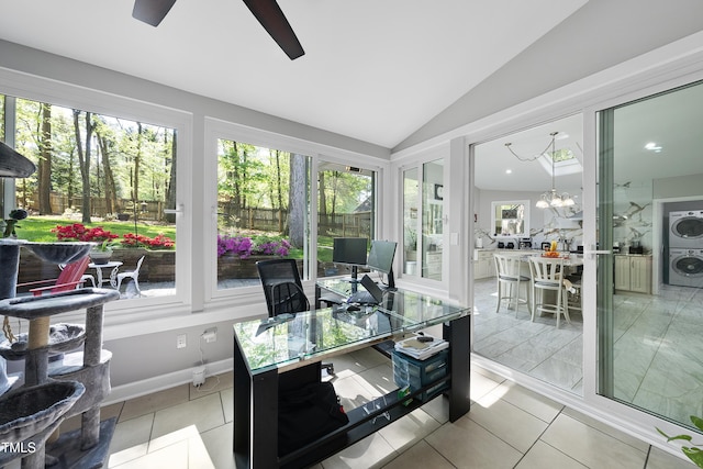 sunroom / solarium featuring tile patterned floors, stacked washer and clothes dryer, an inviting chandelier, and lofted ceiling