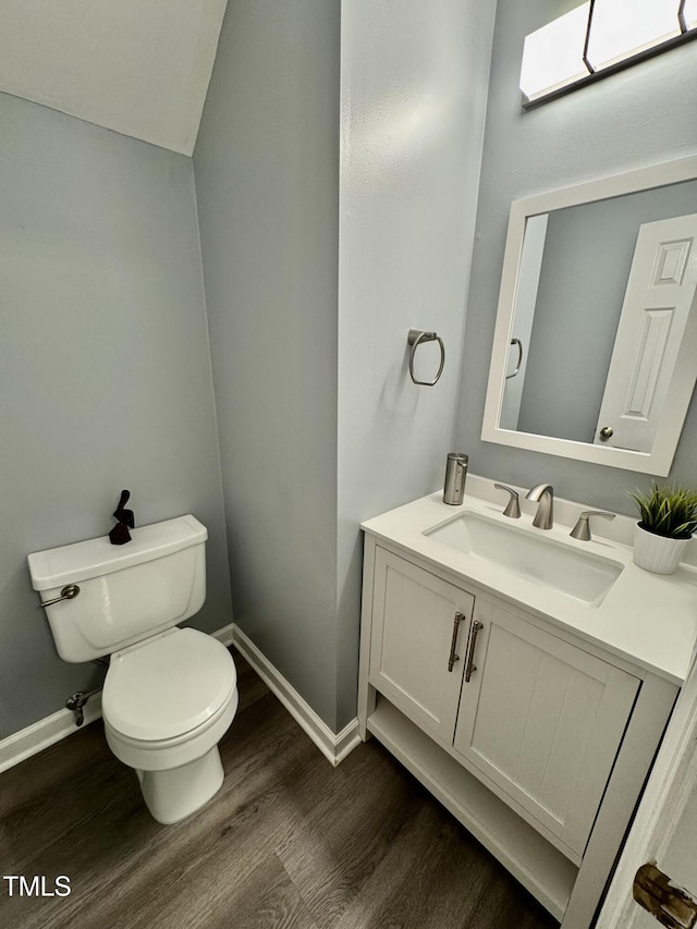 bathroom with toilet, baseboards, wood finished floors, and vanity