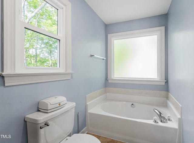 full bathroom featuring toilet, tile patterned floors, and a garden tub