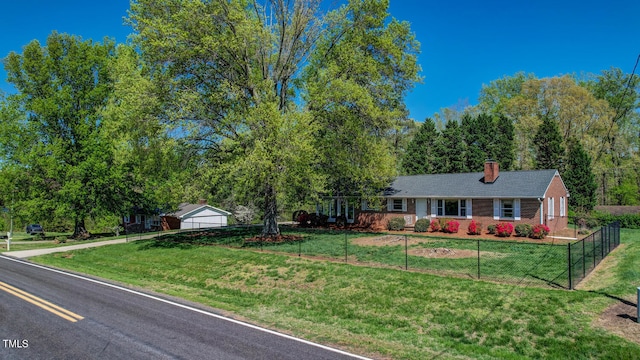 single story home featuring brick siding, a chimney, a front lawn, and a fenced front yard