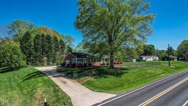view of front of house with driveway, a front lawn, and a fenced front yard