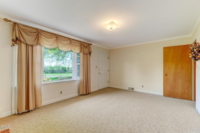 spare room with crown molding, baseboards, carpet, and visible vents