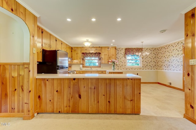 kitchen with a peninsula, light countertops, freestanding refrigerator, visible vents, and a sink