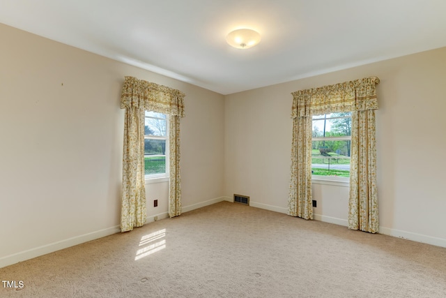 carpeted spare room with a wealth of natural light, visible vents, and baseboards