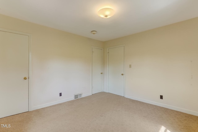 carpeted empty room featuring visible vents and baseboards