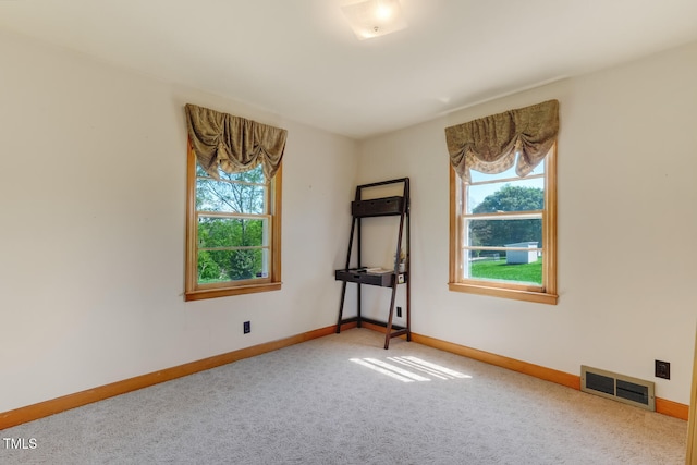 unfurnished room featuring visible vents, a wealth of natural light, carpet, and baseboards