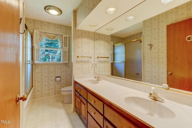 full bathroom with a sink, toilet, double vanity, and wallpapered walls