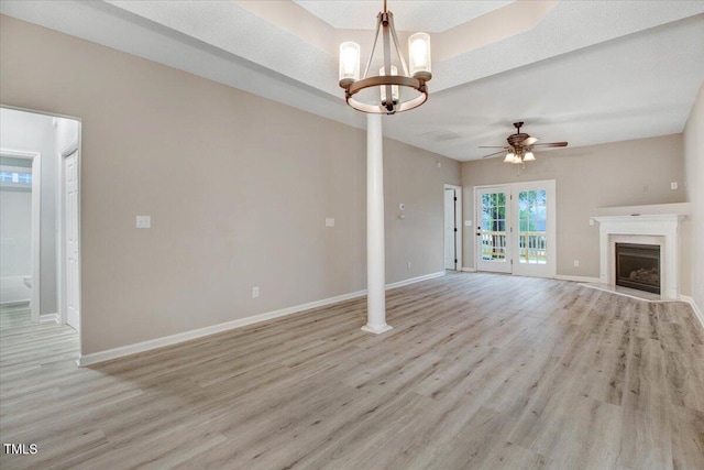 unfurnished living room with a fireplace, light wood-type flooring, ceiling fan with notable chandelier, and baseboards