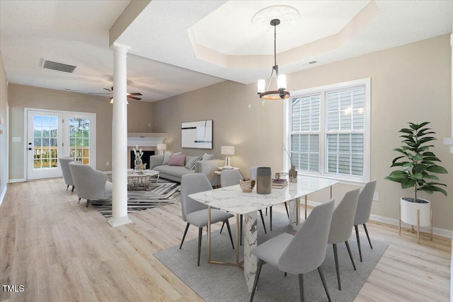 dining space featuring decorative columns, a fireplace, light wood-style flooring, visible vents, and baseboards