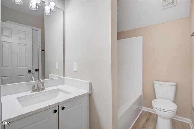 bathroom with visible vents, baseboards, toilet, vanity, and wood finished floors