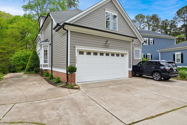 3332 Cheswick Dr, Raleigh, NC 27609 - view of side of home with driveway, a garage, and brick siding