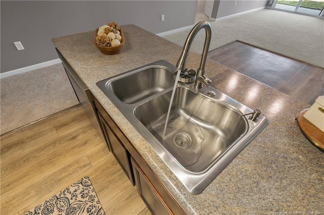 room details featuring baseboards, light wood-style flooring, light colored carpet, and a sink
