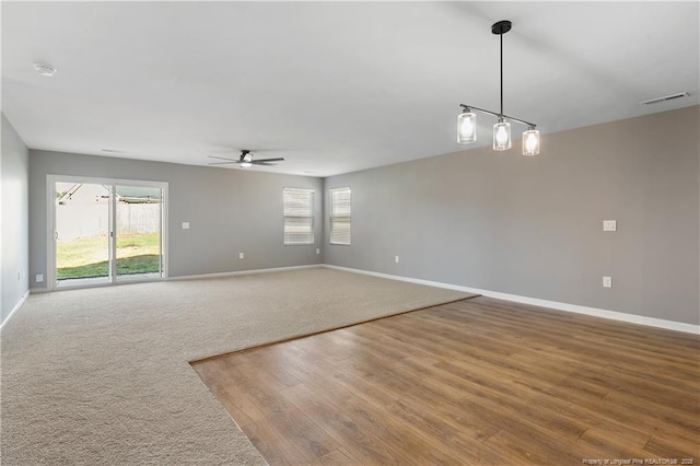 unfurnished room with a wealth of natural light, baseboards, a ceiling fan, and wood finished floors