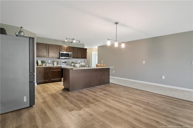 kitchen with dark brown cabinetry, baseboards, light wood-style flooring, light countertops, and stainless steel appliances