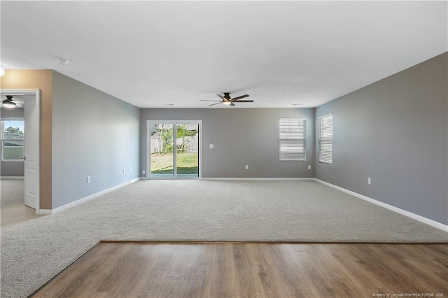 unfurnished living room featuring baseboards, a ceiling fan, and wood finished floors
