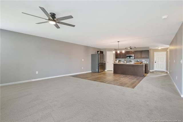unfurnished living room featuring baseboards, a ceiling fan, and carpet