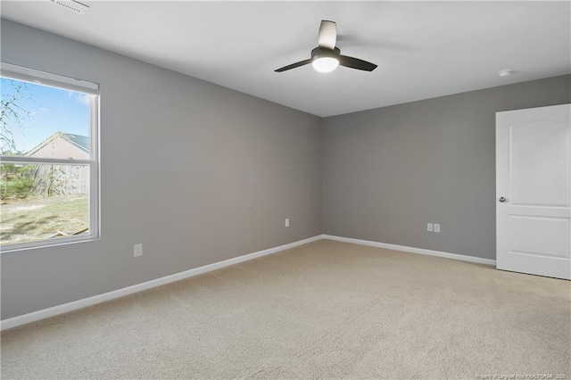 spare room featuring light carpet, baseboards, and a ceiling fan
