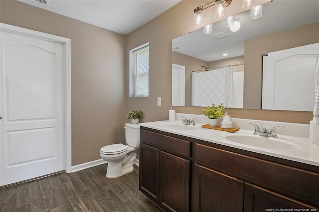 bathroom with a sink, toilet, wood finished floors, and baseboards