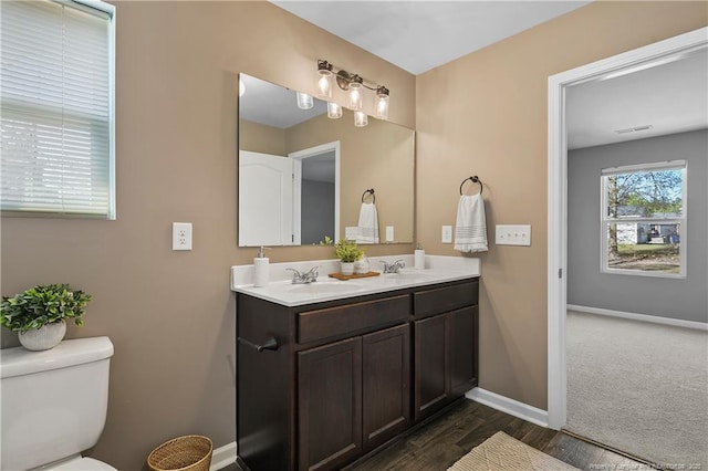 bathroom with double vanity, baseboards, a sink, and toilet