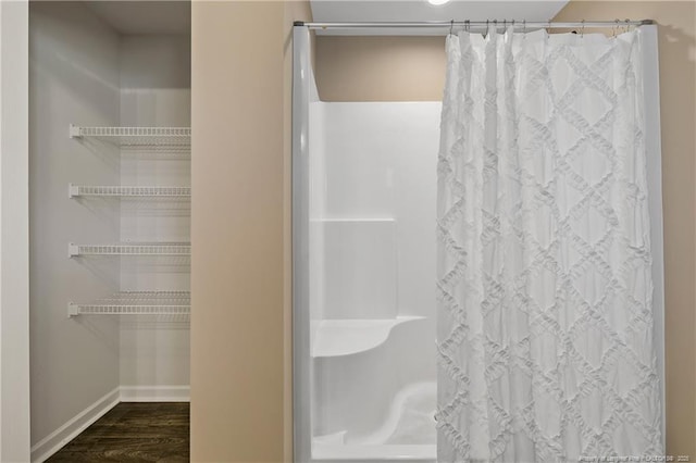 bathroom with baseboards, wood finished floors, and a shower with curtain