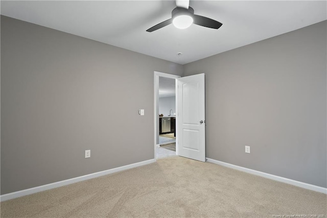 empty room with baseboards, a ceiling fan, and light colored carpet