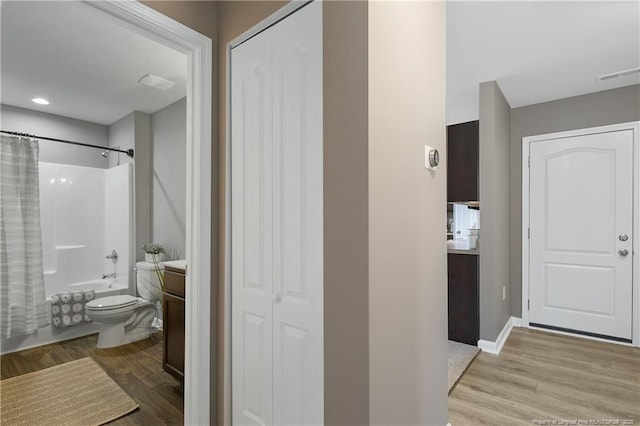 interior space with shower / tub combo, vanity, toilet, visible vents, and wood finished floors
