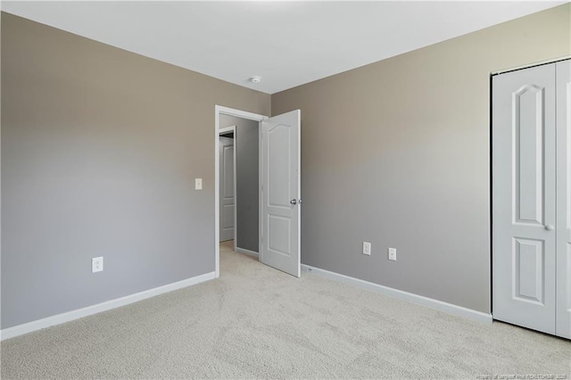unfurnished bedroom featuring a closet, baseboards, and light colored carpet