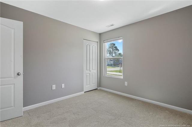 spare room with light colored carpet, baseboards, and visible vents