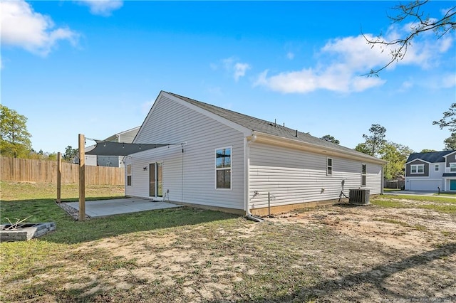 rear view of house with cooling unit, a patio area, fence, and a lawn
