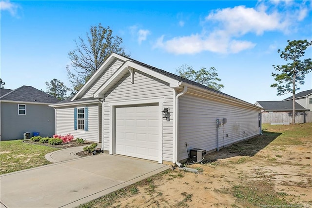 garage featuring concrete driveway and fence