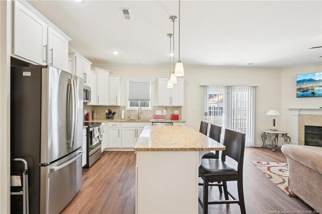 2140 Smith Rd, Hope Mills, NC 28348 - kitchen with tasteful backsplash, a center island, wood finished floors, stainless steel appliances, and open floor plan