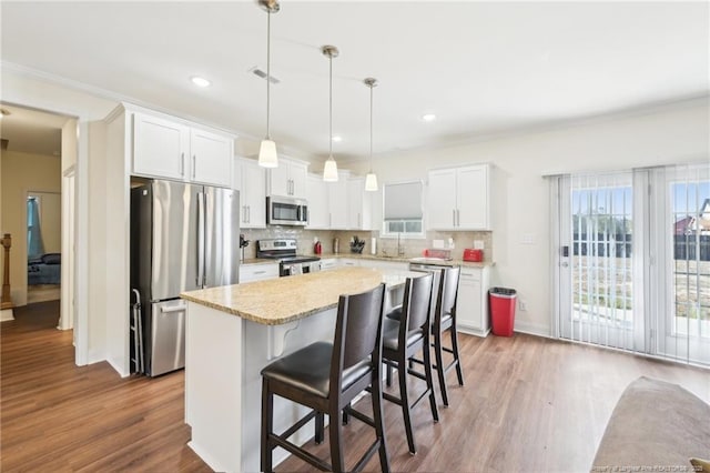 2140 Smith Rd, Hope Mills, NC 28348 - kitchen featuring tasteful backsplash, a kitchen island, white cabinets, appliances with stainless steel finishes, and wood finished floors